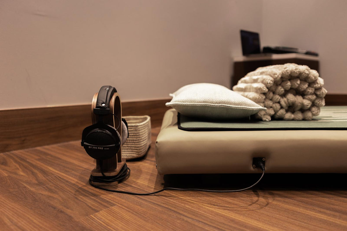 Onizion sound bed with studio headphones on a wooden stand, connected to the bed by cable
