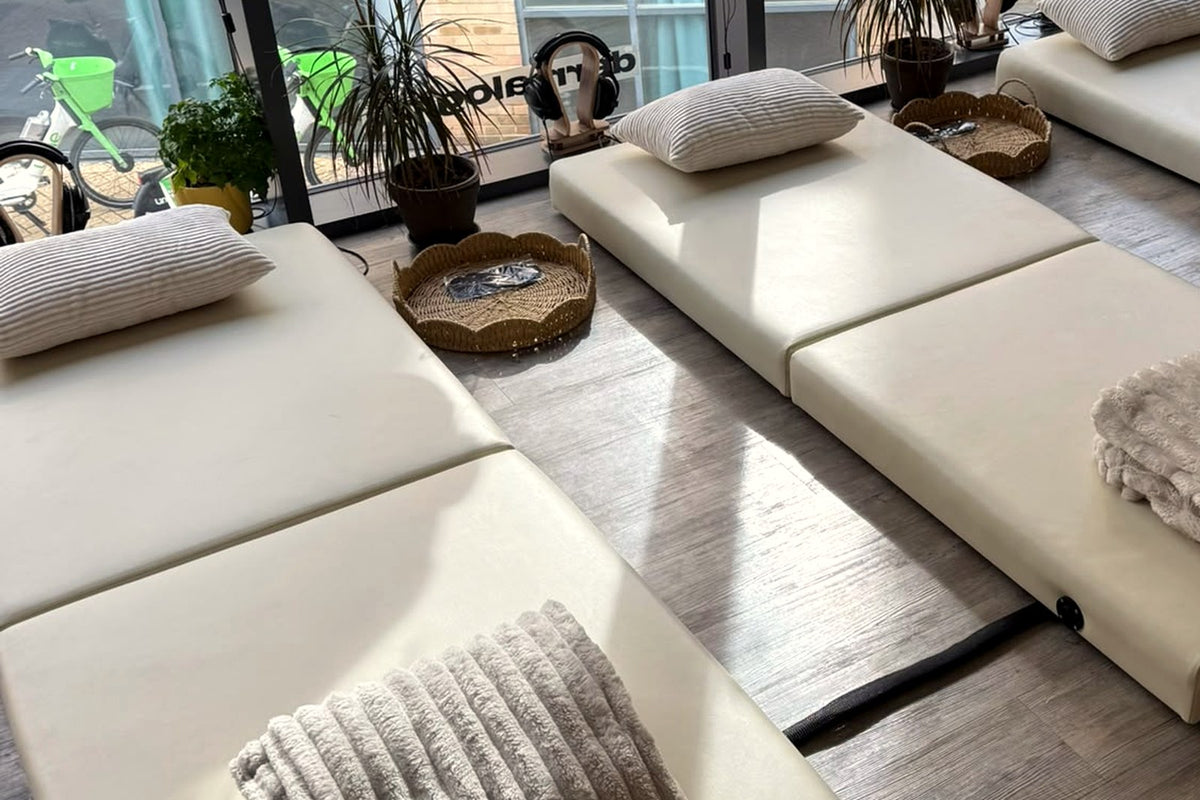Two Onizion sound beds unfolded on a wooden floor, each with a pillow and a soft blanket